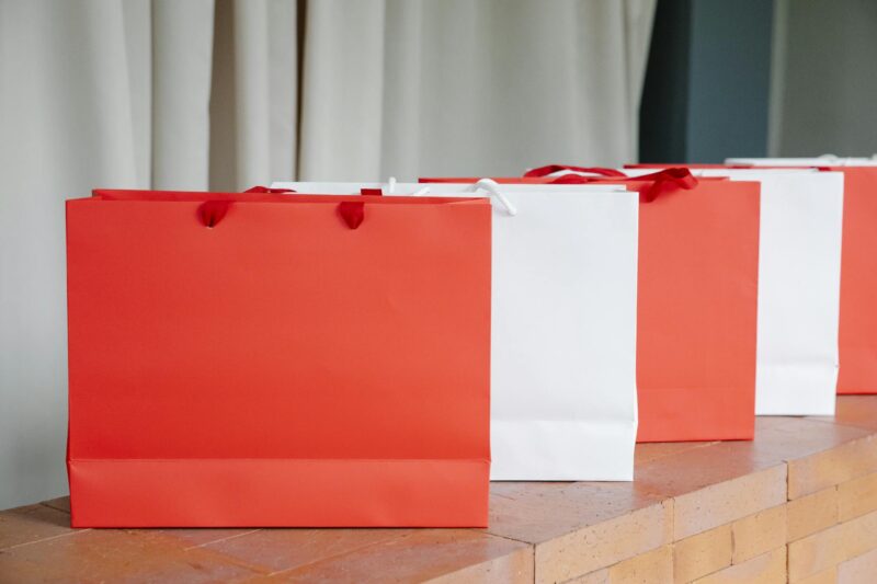 Set of red and white paper shopping bags placed on brick shelf in studio